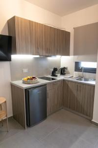 a kitchen with wooden cabinets and a bowl of fruit on the counter at Gaia Apartment II in Parga