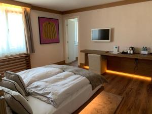 een slaapkamer met een bed en een bureau met een televisie bij Hôtel Rallye & Entrées aux Bains de la Gruyère in Bulle