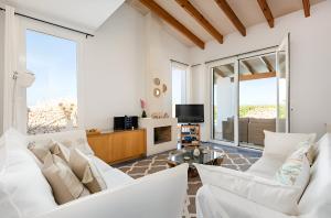 uma sala de estar com mobiliário branco e janelas grandes em Villa Roxana em Es Castell