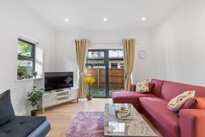 a living room with a purple couch and a tv at Cozy One-Bedroom Retreat in Morden SM4, London in Morden