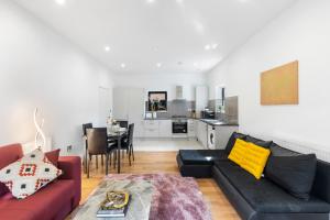 a living room with a black couch and a kitchen at Cozy One-Bedroom Retreat in Morden SM4, London in Morden