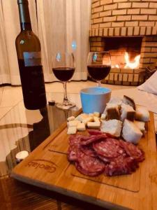 un plateau de découpe en bois avec de la viande et deux verres de vin dans l'établissement Chalé Vô Vilbertinho, pousada com café da manhã!, à Alfredo Wagner