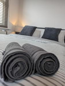 uma cama com três toalhas enroladas em 2 bedroom apartment in Gravesend 10 mins walk from train station with free parking em Gravesend