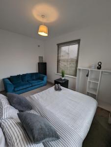 1 dormitorio con 2 camas y sofá azul en 2 bedroom apartment in Gravesend 10 mins walk from train station with free parking, en Gravesend