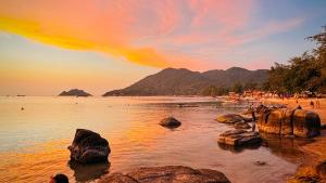a beach with rocks in the water at sunset at Ocean View Resort in Koh Tao