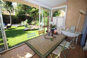 een kamer met een tafel en uitzicht op een tuin bij Valbonne - Villa dans le domaine privé Val d'Azur avec piscine, tennis in Valbonne