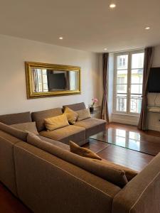 a living room with a brown couch and a mirror at bel appartement chic et cosy 78100 in Saint-Germain-en-Laye
