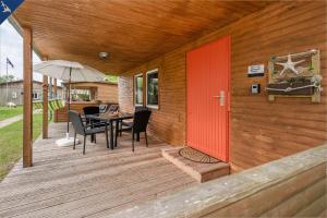 a wooden deck with a red door and a table and chairs at Ferienresort Möwenort Lütow Bungalow 6 in Lütow