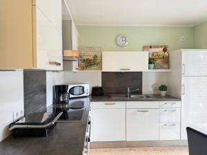a kitchen with white cabinets and a black counter top at Central City Apartment Cloppenburg in Cloppenburg