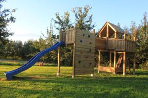 a wooden playground with a slide in a field at B&B 't Zwaluwnest in Heuvelland