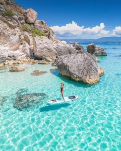 a man standing on a surfboard in the water at Voyager in Cagliari