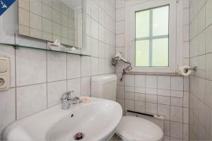 une salle de bain avec un lavabo, des toilettes et un miroir dans l'établissement Ferienresort Möwenort Lütow Bungalow 8, à Lütow 22 autres photos