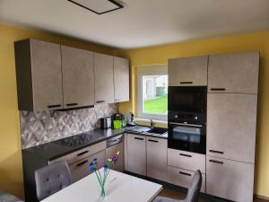 a kitchen with white cabinets and a table and a window at Haus Yuphin in Hart bei Graz