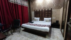 um quarto com uma cama grande e cortinas vermelhas em Swastik Vatika em Ambala