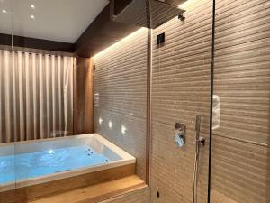 a bathroom with a tub with a glass shower at Alevic Hotel Sirmione in Sirmione