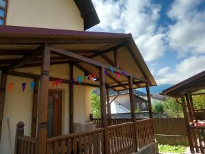 een huis met een houten veranda met vlaggen erop bij Casa Bear Azuga in Azuga