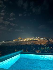 - une piscine avec vue sur la ville la nuit dans l'établissement Vineyard Exclusive Suites, à Akrotiri