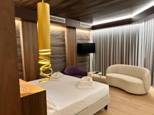 a bedroom with a bed and a chair and a television at Alevic Hotel Sirmione in Sirmione