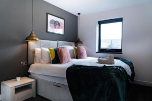 a bedroom with a large white bed with colorful pillows at Midsummer Apartments "Free On-Site Parking & Sky TV" in Peterborough