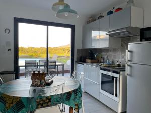 eine Küche mit weißen Geräten und einem Tisch darin in der Unterkunft Casa Albera contemporaine piscine vue montagne in Laroque-des-Albères