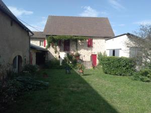 ein weißes Haus mit einer roten Tür und einem Hof in der Unterkunft Gîte à la ferme in Pachins