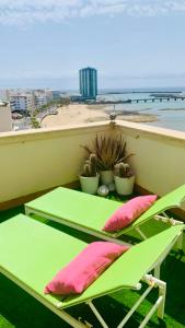 a green table and chairs on a balcony with a beach at Ático El Reducto views in Arrecife
