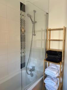 een badkamer met een douche en een bad met handdoeken bij Appartement "Escapade à Malo"pour 4 à 6 personnes 5 mn de la plage in Duinkerke