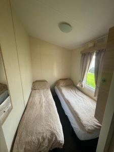 Duas camas num pequeno quarto com uma janela em Atlas festival em Leysdown-on-Sea