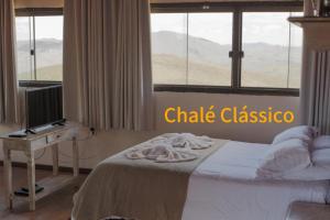 a bedroom with a bed with a desk and a window at Pousada Mirante do Sol in Ouro Preto