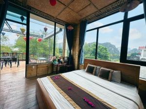 a bedroom with a large bed and large windows at Trang An Moon Garden Homestay in Ninh Binh