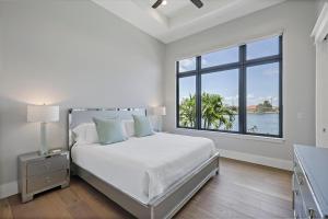 een witte slaapkamer met een bed en een groot raam bij Luxurious home with pool/spa and huge water view in Marco Island +49 foto's