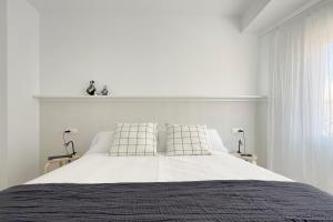 a white bedroom with a large bed with two pillows at Apartamento Boutique en el corazón de Ronda in Ronda