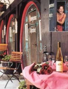 uma mesa com uma garrafa de vinho e uma mulher em Hotel Lindenwirt em Rüdesheim am Rhein