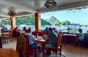 a group of people sitting at tables in a restaurant at La Salangane Beach Hotel - Downtown in El Nido