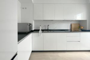 a white kitchen with white cabinets and a microwave at Apartamento Boutique en el corazón de Ronda in Ronda