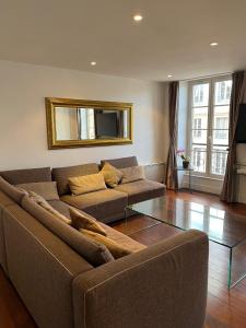 a living room with a couch and a mirror at bel appartement chic et cosy 78100 in Saint-Germain-en-Laye