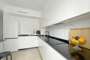 a white kitchen with a bowl of fruit on a counter at Apartamento Boutique en el corazón de Ronda in Ronda +15 photos