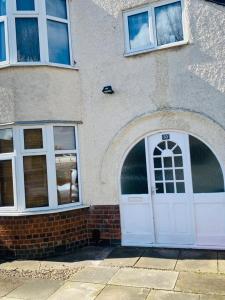 un edificio de ladrillo con una puerta y ventanas blancas en Instant Lodge en Leicester