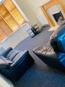 a living room with a leather couch and a chair at Instant Lodge in Leicester