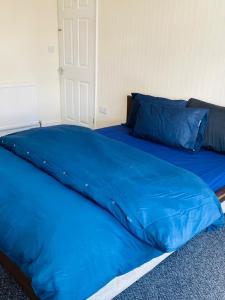 un piumone blu su un letto in una camera da letto di Instant Lodge a Leicester