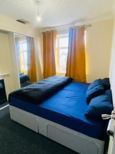 Un dormitorio con una gran cama azul y una ventana en Instant Lodge, en Leicester