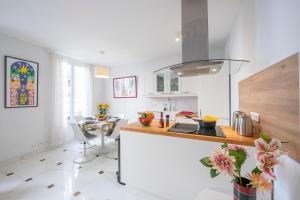 a white kitchen with a counter and a table at Appartement Picasso - Vieil Antibes - Happy Rentals in Antibes
