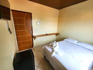 1 dormitorio con 1 cama y puerta de madera en Pousada Nossa Casa Barreirinhas, en Barreirinhas