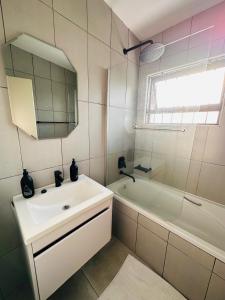 uma casa de banho com um lavatório, uma banheira e um espelho. em The Ultimate Lotus em Manzini