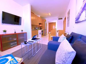 sala de estar con sofá azul y cocina en Tropicalidays Apartamento Zona Centros Comerciales, en Santa Cruz de Tenerife