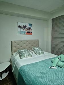 een slaapkamer met een groot bed en een groene deken bij GB Hostel IG in Puerto Iguazú