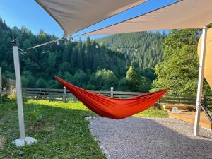 a red hammock is hanging from a tent at White Spring Glamping in Câmpulung Moldovenesc