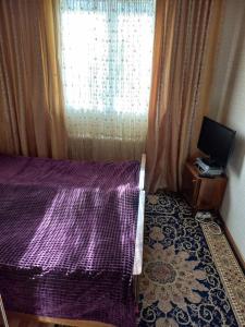 1 dormitorio con cama morada y ventana en A cosy House with a wonderful Garden en Khorog