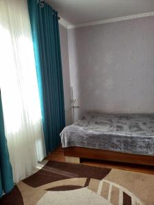 a bedroom with a bed and a window and a rug at A cosy House with a wonderful Garden in Khorog