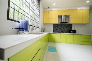 uma cozinha com armários amarelos e brancos e uma janela em De Luma Alma 9 bedroom with 8 bathroom em Bukit Mertajam